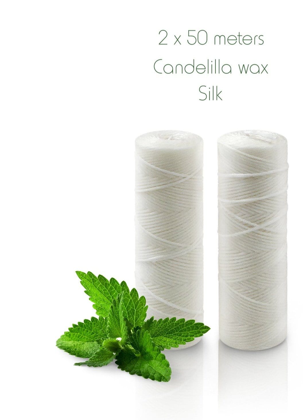 Two white silk floss spools beside mint leaves on Candellila wax Silk packaging