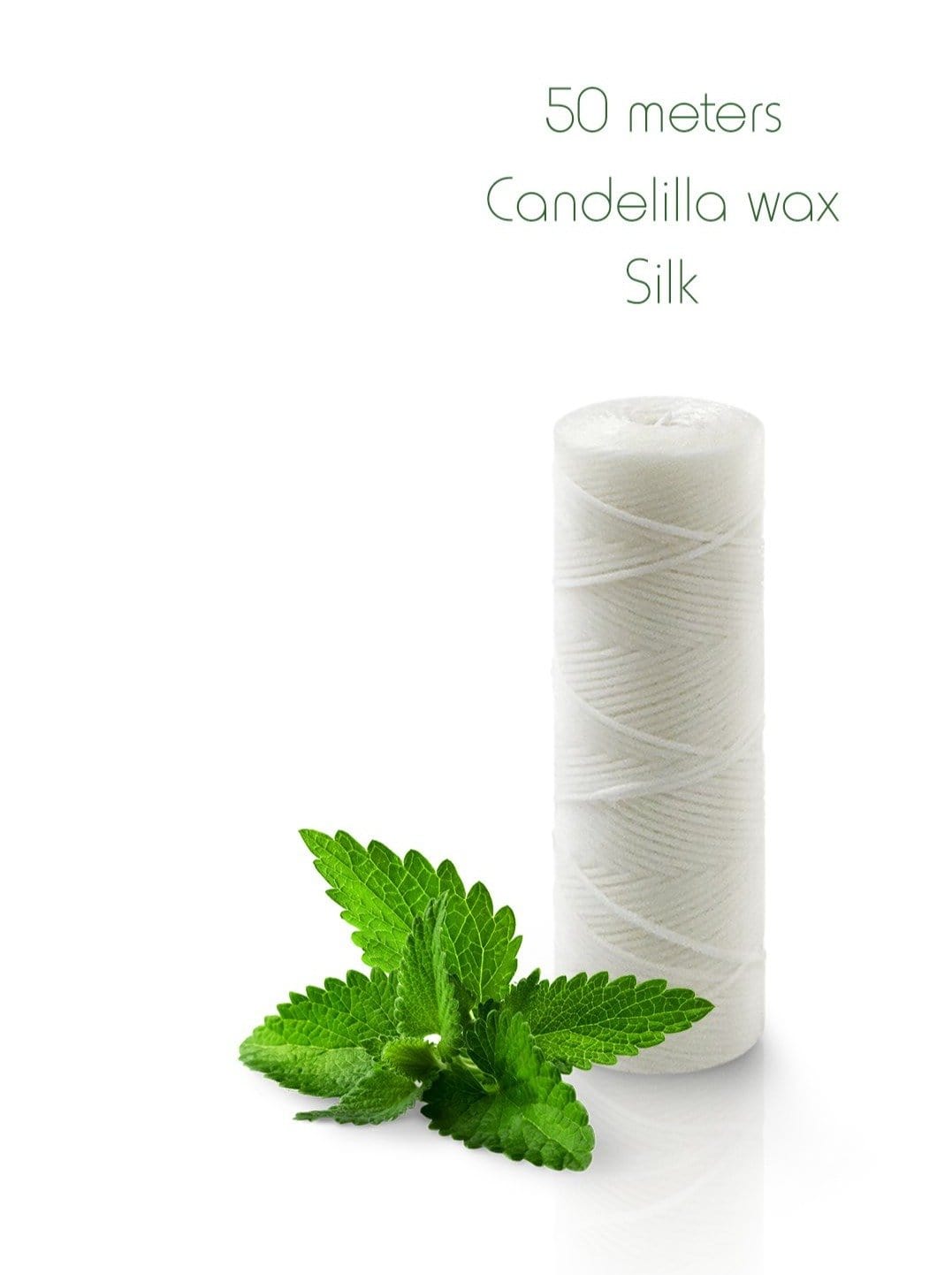 White silk floss spool with mint leaves on a white background