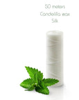 White silk floss spool with mint leaves on a white background
